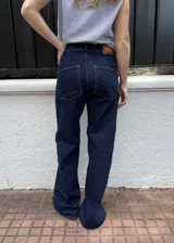 Jean 2 en 1 de color azul oscuro, con corte wide leg transformable a babucha mediante ajuste en los tobillos, tiro alto con cierre frontal de múltiples botones metálicos y bolsillos delanteros destacados.