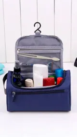 Neceser de viaje color azul, con cierre principal, bolsillo frontal con cierre, asa de mano superior y gancho interno para colgar.