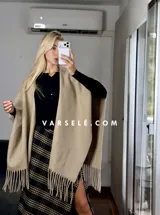 Pollera midi de corte recto con tajo lateral, confeccionada en tela con estampado escocés en tonos marrones, blancos y negros.