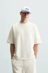 Sudadera de manga corta color marrón oscuro, con cuello redondo y bajo acabado en rib. Presenta un corte relajado y holgado (boxy fit).