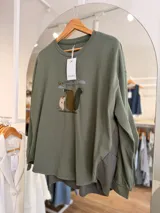 Buzo oversize color verde militar de algodón de media estación, con mangas largas y estampa frontal ilustrada de animalitos. Cuenta con diseño de espalda más larga.
