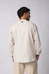 Camisa de manga larga confeccionada en lino, con cuello mao y cierre frontal de botones. Presenta un corte relajado y diseño minimalista.