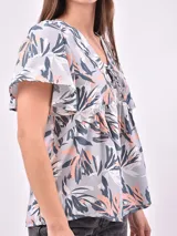 Blusa estampada con cuello en V y lazo ajustable en el escote. Presenta mangas cortas con ligero volumen y un corte holgado con frunces bajo el busto.