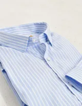 Camisa de vestir de corte clásico, confeccionada en algodón easy iron con diseño de rayas verticales en color celeste y blanco. Presenta cuello camisero rígido y cierre frontal con botones.