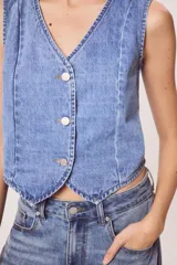 Chaleco de denim celeste con cuello en V y cierre frontal con botones metálicos.