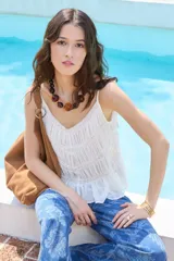 Musculosa de algodón color blanco, con breteles finos, escote en V pronunciado, detalles de encaje y diseño plisado.