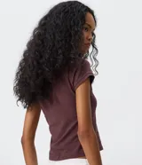 Remera baby tee de algodón color marrón oscuro, con cuello redondo, manga corta y calce ajustado. Presenta un aplique frontal de pedrería brillante con diseño místico de sol, luna y estrella.