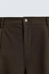 Pantalón chino de corte wide fit confeccionado en tejido de algodón. Presenta pliegues frontales, bolsillos laterales y bolsillos traseros de vivo, con cierre frontal de cremallera y botón.