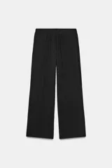 Pantalón fluido de tiro alto color verde militar, con cintura elástica ajustable con cordones y detalles de cuentas de madera. Tiene bolsillos delanteros y pierna recta.