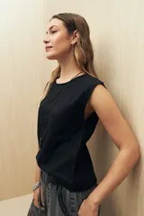 Top sin mangas de lino y viscosa, color negro, con escote redondo y caída relajada. Presenta hombros levemente marcados y botones forrados en la espalda.