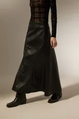 Falda larga de corte evasé confeccionada en cuero sintético negro, con costuras verticales que definen su estructura.