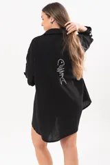 Vestido camisero corto negro, con escote en V, cuello clásico, mangas tres cuartos regulables y detalle de pez bordado a mano en la espalda.