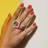 Anillo con diseño geométrico en colores celeste, rojo y plateado.