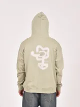 Canguro de tejido grueso color marrón, con capucha y bolsillo canguro frontal. Presenta un estampado minimalista en el pecho con texto y un diseño abstracto.