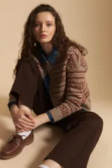 Cardigan corto de tejido jacquard con diseño geométrico en tonos beige y crema, con cierre frontal de botones y cuello redondo.