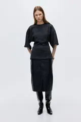 Top de punto fino color gris oscuro, con cuello redondo, costuras decorativas frontales, hombros caídos y mangas al codo. Presenta un corte holgado con bajo levemente acampanado.