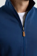 Cardigan de tejido de punto color verde militar, con cierre frontal de metal y cuello redondo. Presenta detalle de tejido plano en la cartera del cierre y en los bolsillos laterales.