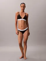 Bralette de triángulo Calvin Klein confeccionado en una mezcla de algodón, modal y elastano. Presenta copas ligeramente forradas sin aro, tirantes ajustables y la icónica banda elástica con el logo de la marca.