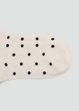 Medias de punto color crudo con estampado de lunares negros.