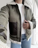 Chaqueta gamulan color verde con interior de piel sintética blanca, cierre frontal con cremallera y detalles en cuero marrón.