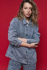 Sobrecamisa de jean de calce relajado color gris, con solapa clásica, bolsillos frontales y cierre de botones metálicos.
