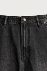 Pantalón jeans relaxed fit de mezclilla azul oscuro, con estilo carpintero que incluye bolsillos laterales y presillas de herramientas. Cuenta con costuras pespuntadas en contraste y cierre frontal con botón y cremallera.