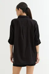 Camisa color crudo, de corte clásico, con cuello camisero, cierre frontal con botones y mangas 3/4 con trabillas.