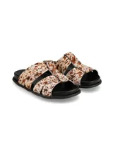 Sandalias planas de cuero con estampa animal print tipo vaca, con tiras cruzadas y suela negra.