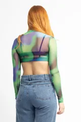 Remera de mesh transparente con cuello alto y estampado abstracto en tonos verde, azul y violeta.