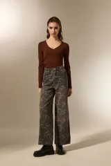 Pantalon de jean estilo baggy con estampado floral en tonos gris oscuro y blanco. Presenta un corte de pierna ancha, tiro medio y cierre frontal con botón y cremallera.
