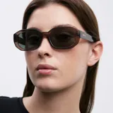 Lentes de sol unisex de forma geométrica, con armazón marrón y lentes polarizadas de color verde oscuro.