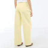 Pantalón de corte globo en color amarillo pastel, con tiro alto, cierre frontal con botón y bolsillos laterales.