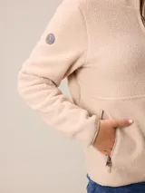 Canguro de sherpa color bordó, con cuello alto y cierre frontal parcial. Presenta un bolsillo con cierre en el pecho y bolsillos laterales, confeccionado en tejido de textura suave y abrigada.