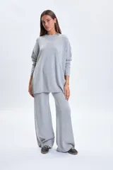 Buzo de punto oversize en color gris melange, con cuello redondo y mangas largas de corte caído.