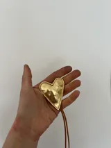 Collar con tres dijes de corazón irregular hechos a mano en alpaca o bronce, con tiento de gamuza negro y cuentas plateadas. El largo del tiento permite darle varias vueltas o usarlo largo.