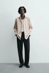 Camisa slim fit color beige, confeccionada en tejido de algodón, con cuello italiano y manga larga con puño de botón. Cierre frontal de botonadura.