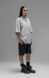 Camisa de manga corta y corte holgado con diseño de bordado broderie en toda la prenda, cuello camisero y cierre frontal de botones.