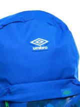 Mochila negra con bolsillo frontal que presenta un estampado abstracto en tonos rojos y negros, con el logo Umbro en blanco superpuesto. Incluye logo Umbro bordado en rojo en la parte superior y un bolsillo lateral de malla para botella.