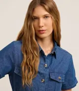 Vestido midi de jeans azul con cuello inglés, manga corta, abotonado delantero, bolsillos utilitarios y cinturón con hebilla redonda.