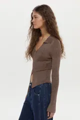 Cardigan tejido en rib con hilado de lurex, color crudo, calce al cuerpo, cuello polo, mangas largas con aberturas y cierre metálico frontal bidireccional.