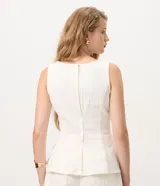 Blusa peplum sin mangas en sarga de algodón blanca, con escote redondo y diseño estructurado con volado amplio en el ruedo.