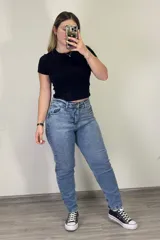 Pantalón jean mom celeste de tiro alto, corte holgado y tobillos ajustados.