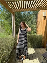 Vestido largo de punto a rayas horizontales negras y blancas, sin mangas, con cuello redondo y volados blancos en cuello y sisas.