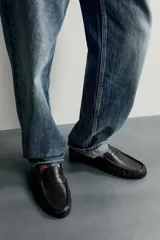 Mocasín de vestir negro confeccionado en piel, con detalle fruncido en la parte delantera y antifaz en el empeine. Cuenta con suela a tono y ligero tacón.