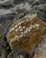 Pulsera de diseño artesanal elaborada eslabón por eslabón a mano, con eslabones circulares texturados de metal dorado y cadena regulable.