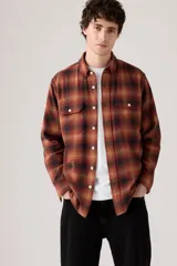 Camisa de manga larga a cuadros en tonos rojo, naranja y negro, con dos bolsillos frontales con solapa y botones blancos.