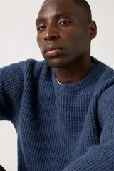 Sweater de punto grueso color azul marino, con cuello redondo y manga larga.