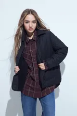 Campera acolchada de color negro con diseño capitoneado, cierre frontal con botones y cuello clásico.