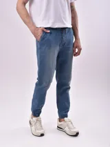 Pantalón jogger de denim celeste con cintura elástica ajustable con cordón, bolsillos laterales y puños elásticos.