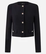 Chaquetilla ligera color negro de crepé de poliéster, con cuello redondo, manga larga y cierre frontal de botones dorados grabados. Cuenta con bolsillos frontales con solapa decorativa y botones a juego.